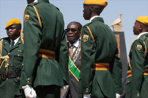 Zimbabwe's President Robert Mugabe (C) inspects an honour guard during Heroes Day commemorations in Harare on August 10, 2015.