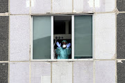 Medical staff in protective gear wave from the intensive care unit of La Paz Hospital, during a partial lockdown as part of a 15-day state of emergency to combat the coronavirus outbreak in Madrid, Spain, on March 18 2020. 