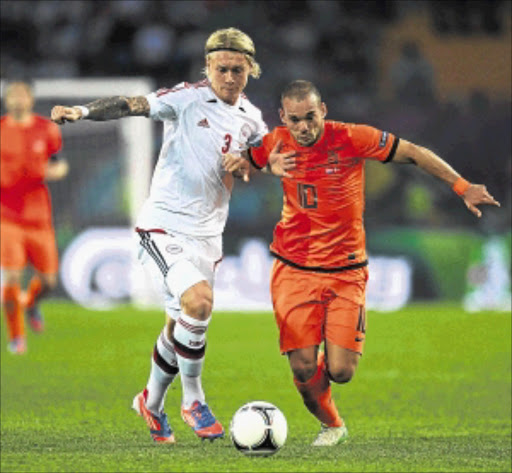 HUFFING AND PUFFING: Denmark's Simon Kjaer, left, battles for the ball with Netherlands's Wesley Sneijder during their Euro 2012 Group B match at Metalist Stadium in Kharkiv, Ukraine, on Saturday. Photo: Getty Images