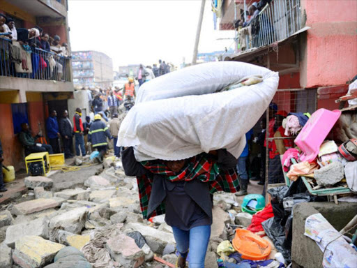 A man carries his belongings away as rescue workers search for those feared trapped in the rubble of a six-storey building that collapsed after days of heavy rain, in Nairobi, Kenya April 30, 2016. REUTERS