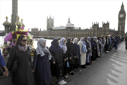 STANDING TALL: Women hold hands in silence on Westminster Bridge, London, in remembrance of the victims of last week's attack.