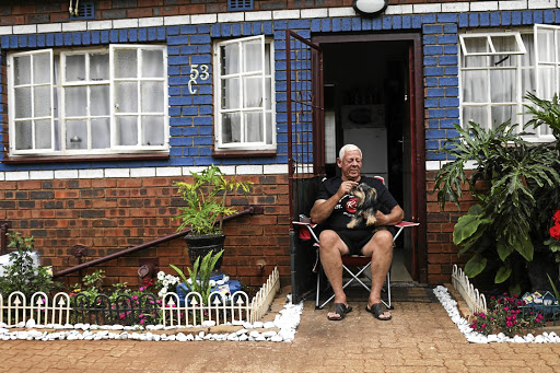 Johan van der Merwe poses for a portrait with his Yorkie, Amy, outside his home in Fietas, Johannesburg.