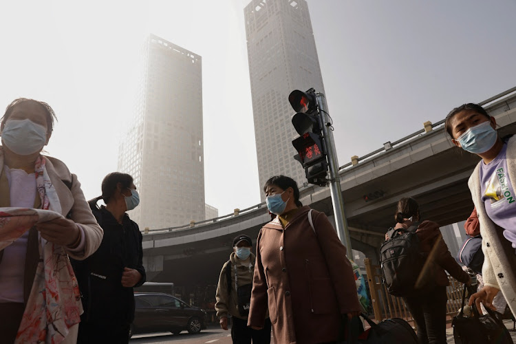 People wait at an intersection in Beijing's central business district in China. Picture: TINGSHU WANG/REUTERS