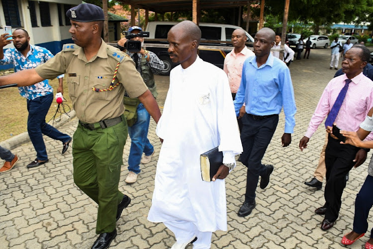 Detectives escort Ezekiel Ombok Odero, the head of New Life Prayer Centre/Church in Kilifi County, at the police headquarters for investigations into alleged deaths of his followers in Mombasa, Kenya, on April 27 2023.