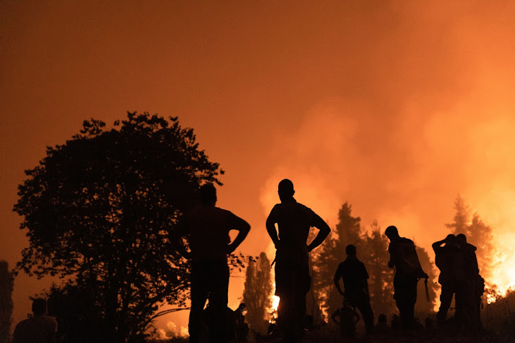 Locals watch the wildfire outside the village of Kamatriades, on Evia island, Greece, on Monday, August 9 2021. Picture: BLOOMBERG/KONSTANTINOS TSAKALIDIS