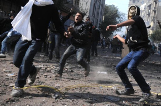 Egyptian protesters throw stones during clashes with riot police along a road which leads to the Interior Ministry, near Tahrir Square, in Cairo. File photo.