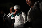 People pray near the site of a building that collapsed in George.