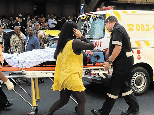 SHOT IN THE HEAD: Paramedics rush Constable Eddie Ngobeni from the Pretoria Magistrate's Court after he was critically injured while trying to save his colleague, Sergeant Theophilus Mogafe