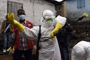 Medical staff members of the Croix Rouge NGO put on protective suits before collecting the corpse of a victim of Ebola. Picture Credit: AFP