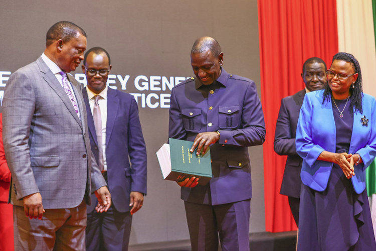 President William Ruto samples a copy of the 24th annual supplement of the Laws of Kenya ad Attorney General Justin Muturi (extreme left) and Chief Justice Martha Koome and Solicitor General Shadrack Mose looks on during the launch at Safari Park hotel on April 30, 2024.