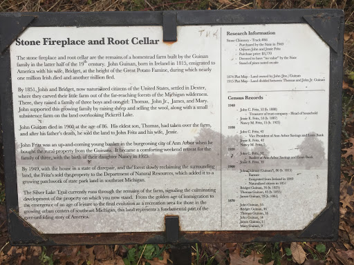 The plaque reads: The stone fireplace and root cellar are the remains of a homestead farm built by the Guinan family in the latter half of the 19th century.  John Guinan, born in Ireland in 1815,...