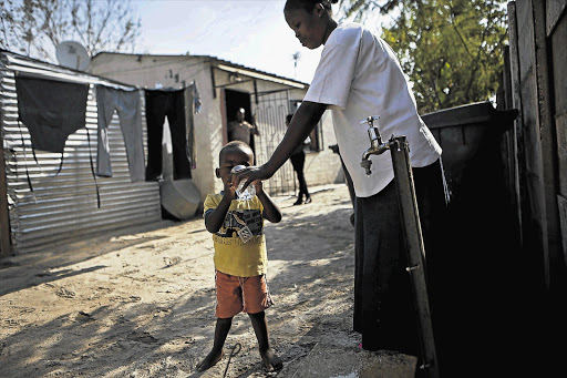 Thembi Mogoba gives her son, Kgothatso, water from a tap outside their home in Diepsloot, north of Johannesburg. Diepsloot residents experienced problems with drinking water in the area earlier this year