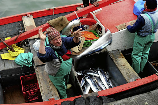 A fisherman off-loads his catch to eager buyers in Cape Town’s Kalk Bay harbour. Picture: REUTERS