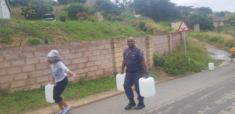 Constable Ricardo Naicker helps a resident carry water after metro police took on the job of operating water tankers on Tuesday May 7 2019.