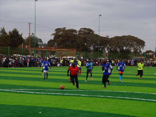 Kiambu Governor William Kabogo (in red) dribbles the ball during a match to mark the opening of Gikambura 11-Aside Football Stadium, Kikuyu, on Sunday /GEORGE MUGO