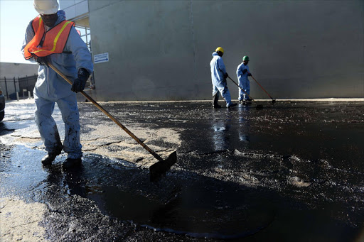 Workers clean up after an above ground oil pipeline ruptured causing some 10,000 gallons of crude oil to spill into the streets of Los Angeles. AFP PHOTO