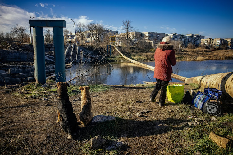A local resident stands next to a destroyed bridge in Bakhmut, Donetsk region, on November 29, 2022, amid the Russian invasion of Ukraine. Once known for its vineyards and cavernous salt mines, Bakhmut has now been dubbed "the meat grinder" due to the brutal trench warfare, artillery duels and frontal assaults that have defined the brutal fight for the city for over six months. (Photo by Yevhen TITOV / AFP)
