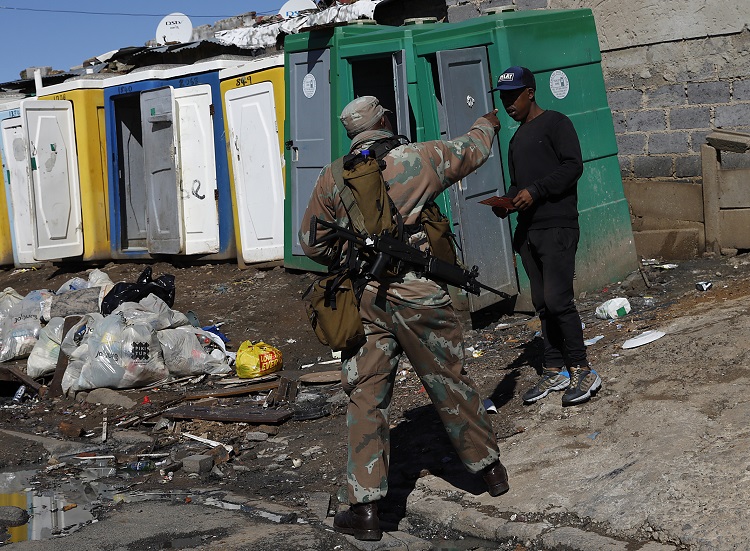 A soldier deployed in Alexandra interacts with a resident. The writer says the plan presented in parliament on Wednesday suggests that the troops have been called to increase the state's capacity for a comprehensive health response to the outbreak.