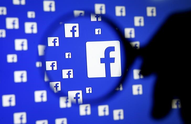 A man poses with a magnifier in front of a Facebook logo on display. Picture: REUTERS/DADO RUVIC