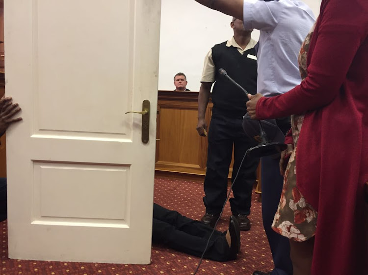 Murder accused Jason Rohde watches as Spier maintenance man Desmond Daniels demonstrates in the High Court in Cape Town on Wednesday how he found Susan Rohde's body behind the bathroom door of the couple's hotel room.