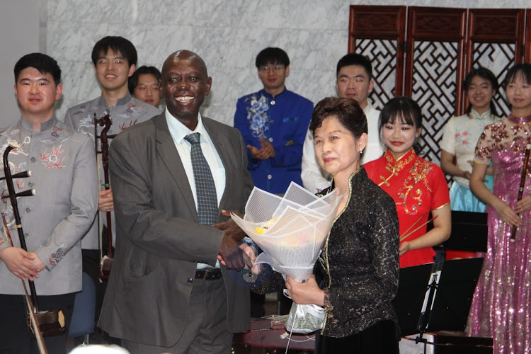 UoN Director of Corporate Affairs John Orindi gifts Nanjing University traditional instrument orchestra choir conductor Prof. Zhang Jingbo a bouquet of flowers during the diversity, beauty and harmony traditional Chinese musical instrument performance at the University of Nairobi main campus on April 18, 2024