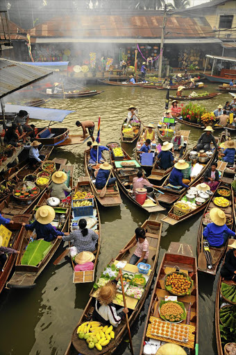 Vendors sit in boats loaded with goods for sale in Amphawa Floating Market.