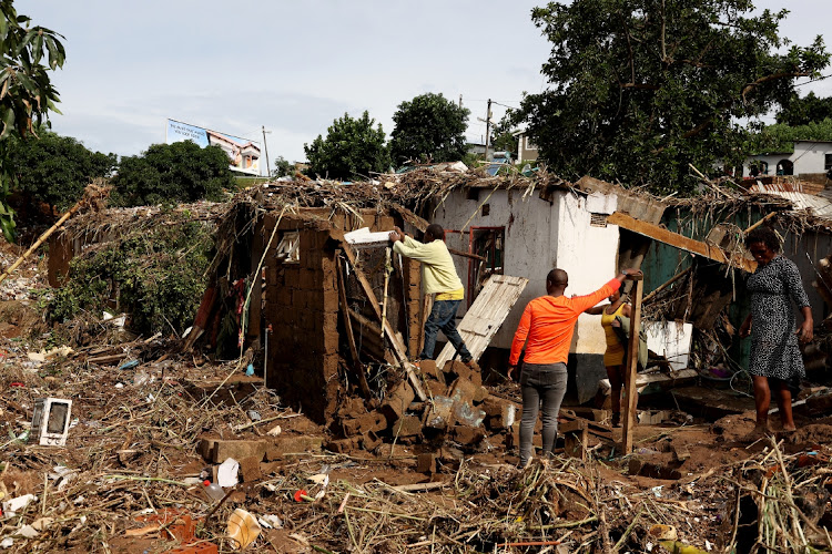 A family inspects their damaged home in Nhlungwane near Ntuzuma.