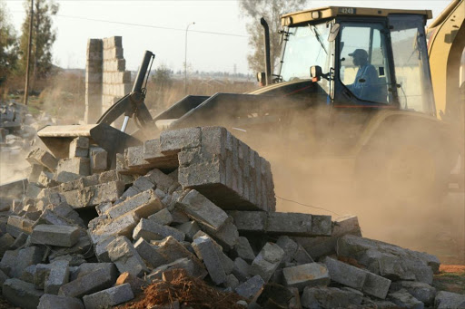 A catapillar at work during the structural demolition by the Department of Housing. File picture.