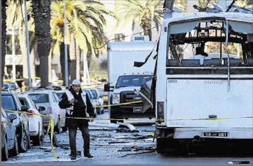 COMBING FOR CLUES: Tunisian forensic police inspect the wreckage of a bus after 13 people were killed in a suicide bomb attack on a bus transporting Tunisia’s presidential guard in Tunis, yesterday