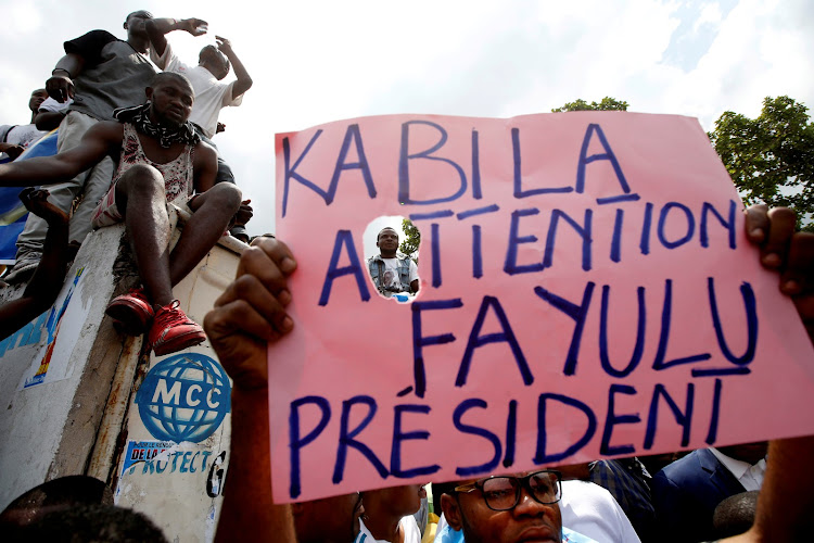 Supporters of the runner-up in Democratic Republic of Congo's presidential election, Martin Fayulu, hold a sign before a political rally in Kinshasa on January 11 2019.