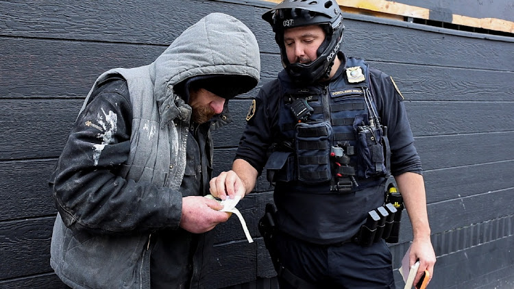 Portland police officer David Baer issues a citation to a man caught smoking fentanyl in downtown Portland, Oregon, US, on February 7, 2024. Baer also includes a business card bearing the number of a 24-hour treatment hotline, which the man can call to get the citation dismissed. Picture: REUTERS/DEBORAH BLOOM