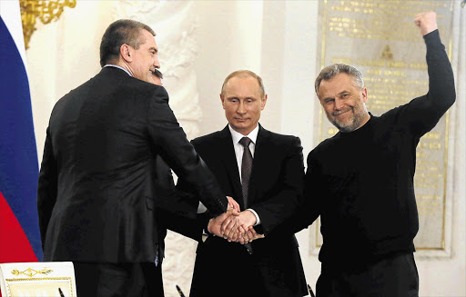 SEALING THE DEAL: Russian President Vladimir Putin, centre, with Crimean Prime Minister Sergei Aksyonov, Crimean parliament speaker Vladimir Konstantinov, obscured, and Alexei Chaly, Sevastopol's new de facto mayor, after signing a unification treaty yesterday