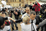 Olympic and Paralympic track star Oscar Pistorius, right, is hugged by a supporter at the Pretoria High Court as he arrives for his trial for the murder of his girlfriend Reeva Steenkamp.