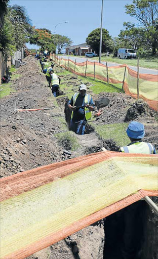 GOOD GROUNDWORK: Workers lay fibre optic infrastructure in trenches down Beacon Bay’s Quenera Drive Picture: ALAN EASON