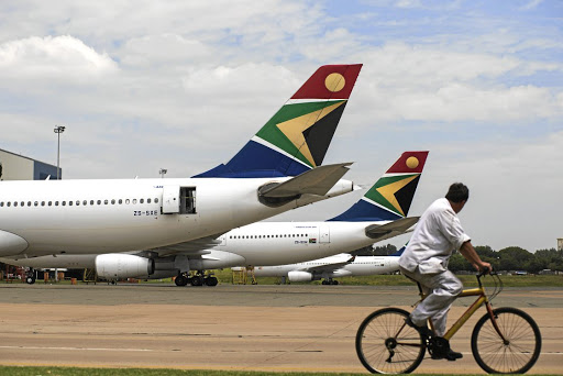 A man cycles past aircraft in the SAA fleet parked at OR Tambo International Airport. Picture: GETTY IMAGES