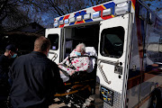 EMS paramedics transport an 82-year-old woman suffering from possible symptoms after she was exposed to a Covid-19 positive family member, in Shawnee, Oklahoma, US, on January 12 2022. 