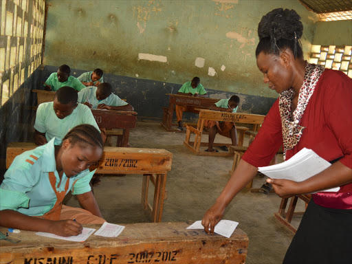 An invigilator distributes KCPE maths papers at Mtopanga primary school in Kisauni,Mombasa during the 2016 exams./FILE