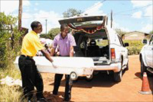 BRUTALITY: Officials load a casket containing the victim's body into a hearse. Pic. Andrew Hlongwane. 17/02/08. © Sowetan.