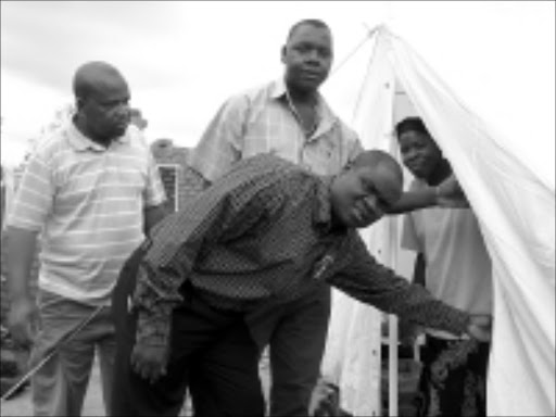 COMPASSION: Ward 12 councillor Stone Ngobeni, Evans Moseamedi and Michael Rabothata of the disaster management unit with a victim of the storm who received a tent from the municipality. 19/11/08. Pic. Michael Sakuneka. © Sowetan.