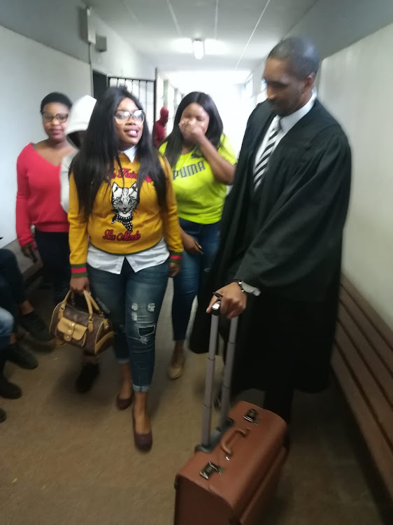 WSU student Sibongile Mani (in the yellow) walks out of the East London regional court