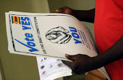 A man holds up posters calling on Zimbabweans to vote yes for the constitutional referendum to be held in country over the weekendto vote for the new constitution in Harare on March 14, 2013.