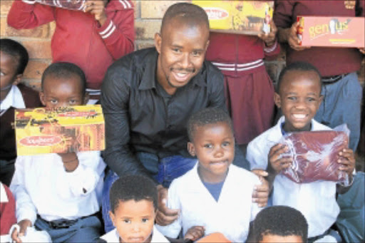 HELPING HANDS: Pupils of Wezibuluko Primary School in Klipspruit, Soweto, receive new school uniforms and shoes from caring civilian Mandla Ncube and his friends and colleagues. phoTO: BUSISIWE MBATHA
