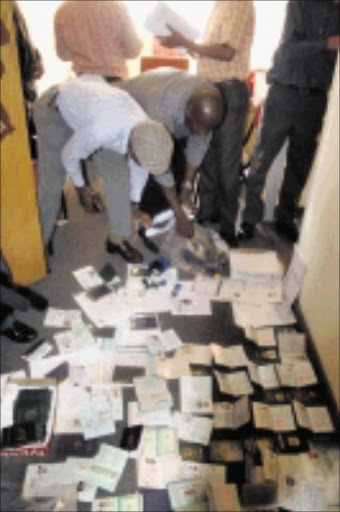 BUST: Police check illegal documents recovered at a bogus Home Affairs office in Gandhi Mall, Joburg. Pic: Bafana Mahlangu. 15/09/2009. © Sowetan. BMA A sign on the door of a bogus Home Affairs reads " Green book imigration" situated on the 3rd floor in Gandhi Mall, central Johannesburg. The owners manufacture fake documentation on the premises for a fee. The owner was busted by the police and Department of Home Affairs officials after a tip-off by the client who was requested to pay R11 000.00 to collect his immigration document. Pic: Bafana Mahlangu. 15/09/2009. © Sowetan.