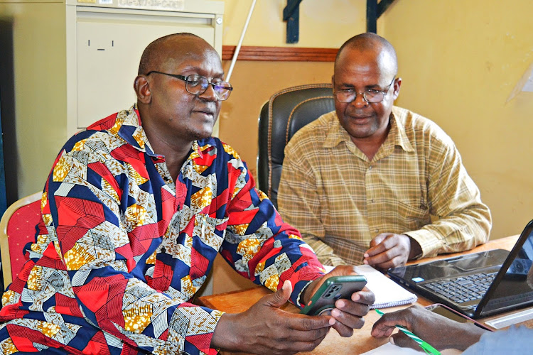 Joshua Mutembei, the director of administration in the Kitui County department of public works, transport and boda boda consults with the ward administrator for Tharaka ward, Japheth Mukuru, during his visit on Thursday to the ward to oversee vetting of boda boda riders destined for training.