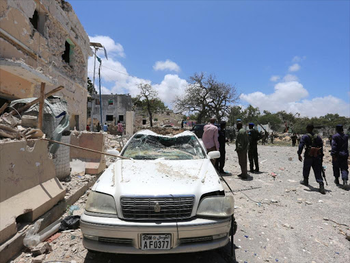Somali government forces walk past a car destroyed as they arrive to secure the scene of a car bomb claimed by al Shabaab Islamist militants outside the president's palace in the Somali capital of Mogadishu, August 30, 2016 /REUTERS
