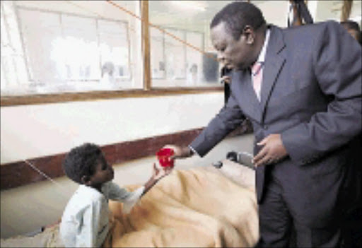 HELPING HAND: Morgan Tsvangirai gives a cup of clean water to a cholera patient at the Budiriro Clinic in Harare. 22/01/2009. © AP Photo. Pic. Tsvangirayi Mukwazhi.