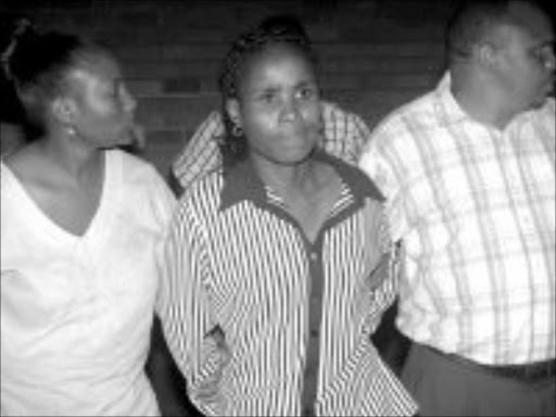 Policewoman Christina Molokomme, centre, being led to the holding cells after her court appearance for allegedly hiring hitmen to kill her husband. Pic. Edward Maahlamela. 19/12/2006. © Sowetan.