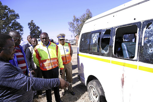 KwaZulu-Natal MEC for transport and community safety Mxolisi Kaunda is briefed by SAPS at the scene of the attack that claimed 11 Ivory Park Taxi Association members.