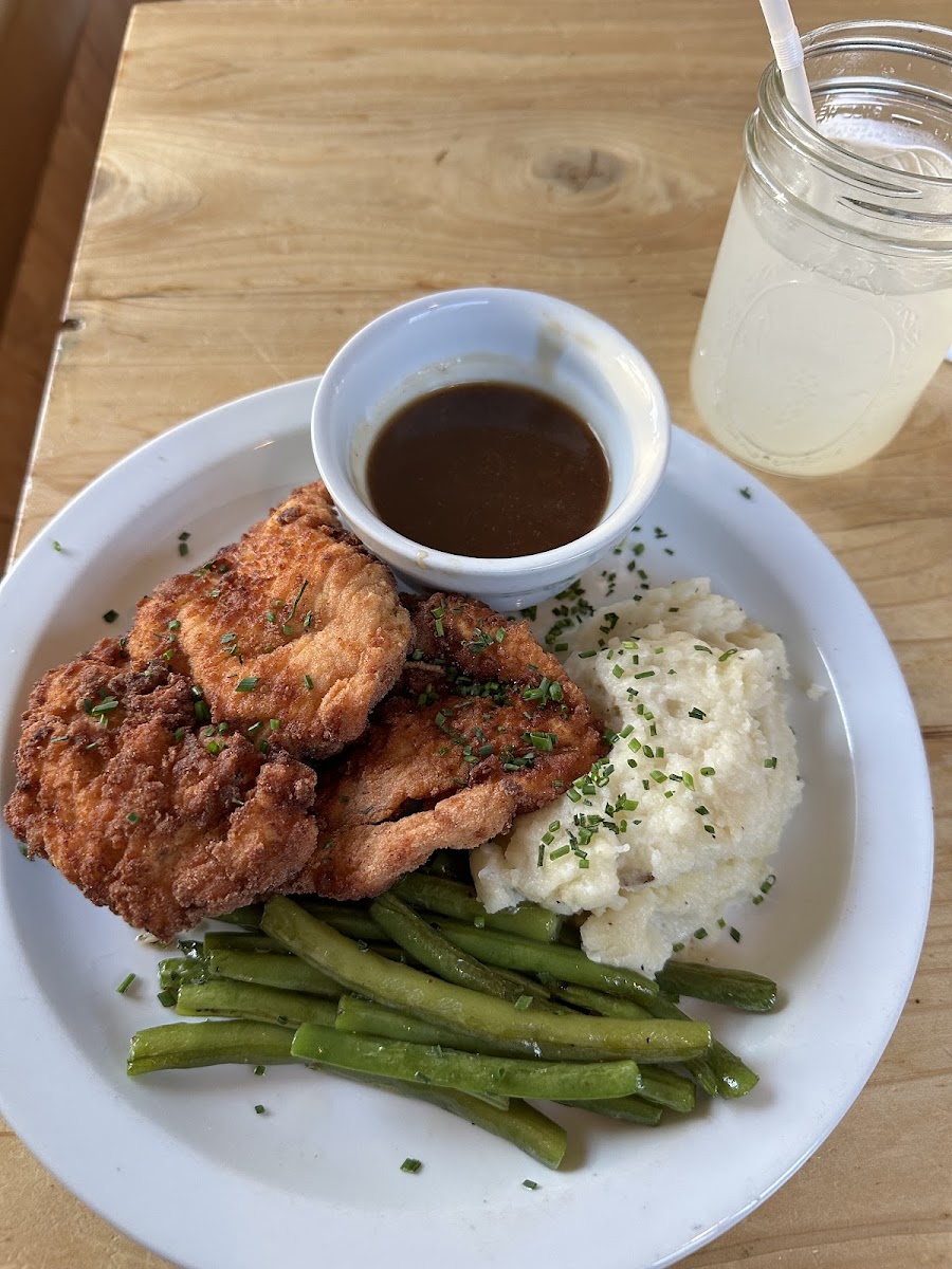 Fried chicken dinner with gravy, mash potatoes, and green beans