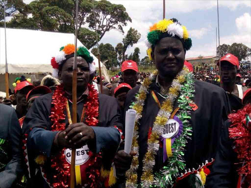 west pokot senator John Lonyangapuo (left) with Kenya civil aviation authority Chairman Samuel Poghisio join traditional dancers in a jig at Kaptabuk secondary school.